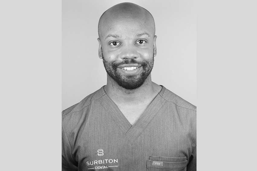 Black and white headshot portrait of Dr Keiron wearing scrubs at Surbiton Dental