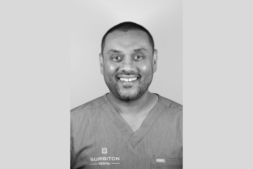 Black and white headshot portrait of Dr Minesh smiling at Surbiton Dental