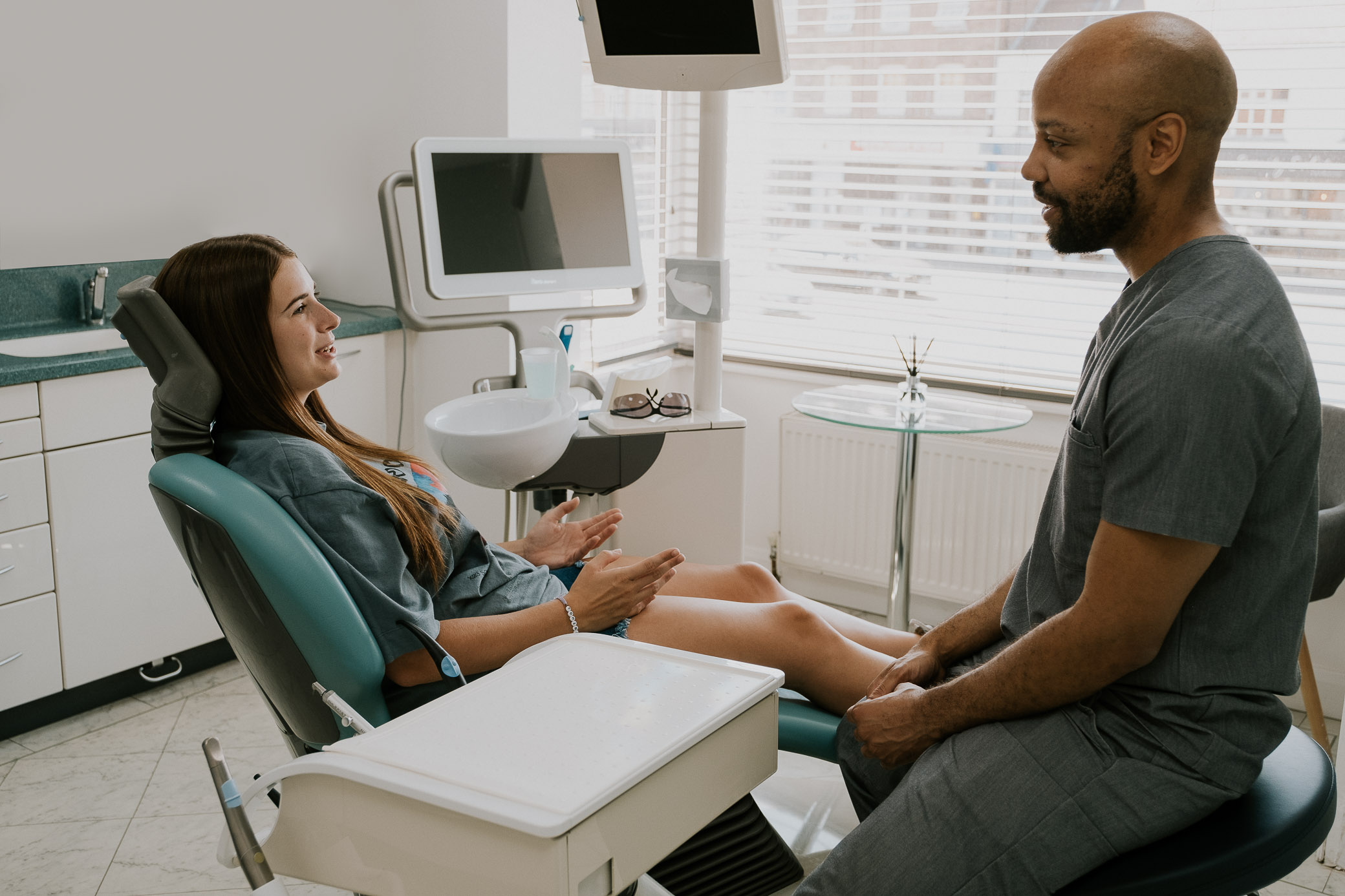 Dentist sitting comfortably and discussing oral health care with a patient in the chair