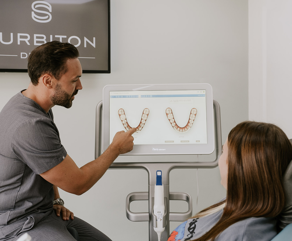 Dentist pointing at 3D digital iTero dental scan screen while explaining treatment roadmap to patient